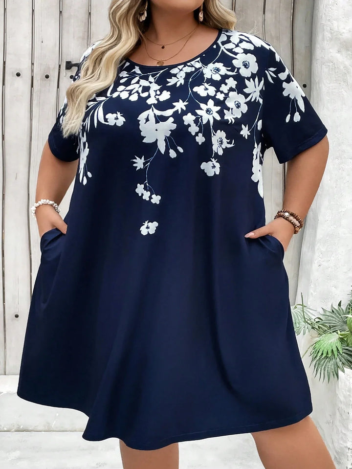 Vestido T-shirt con bolsillos asimétricos y estampado floral en tallas cómodas, adecuado para vacaciones, outfits de verano para mujeres, vestidos de playa, vestidos de graduación o para el té.