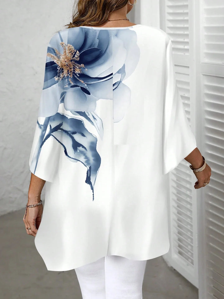 Blusa amplia con escote redondo, mangas 3/4 y dobladillo asimétrico, con estampado floral, disponible en tallas cómodas, adecuada para vacaciones